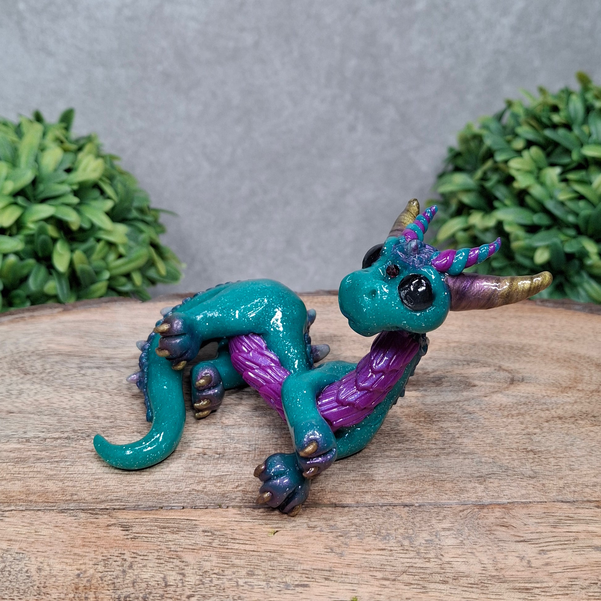 A clay dragon against a wood background with greenery