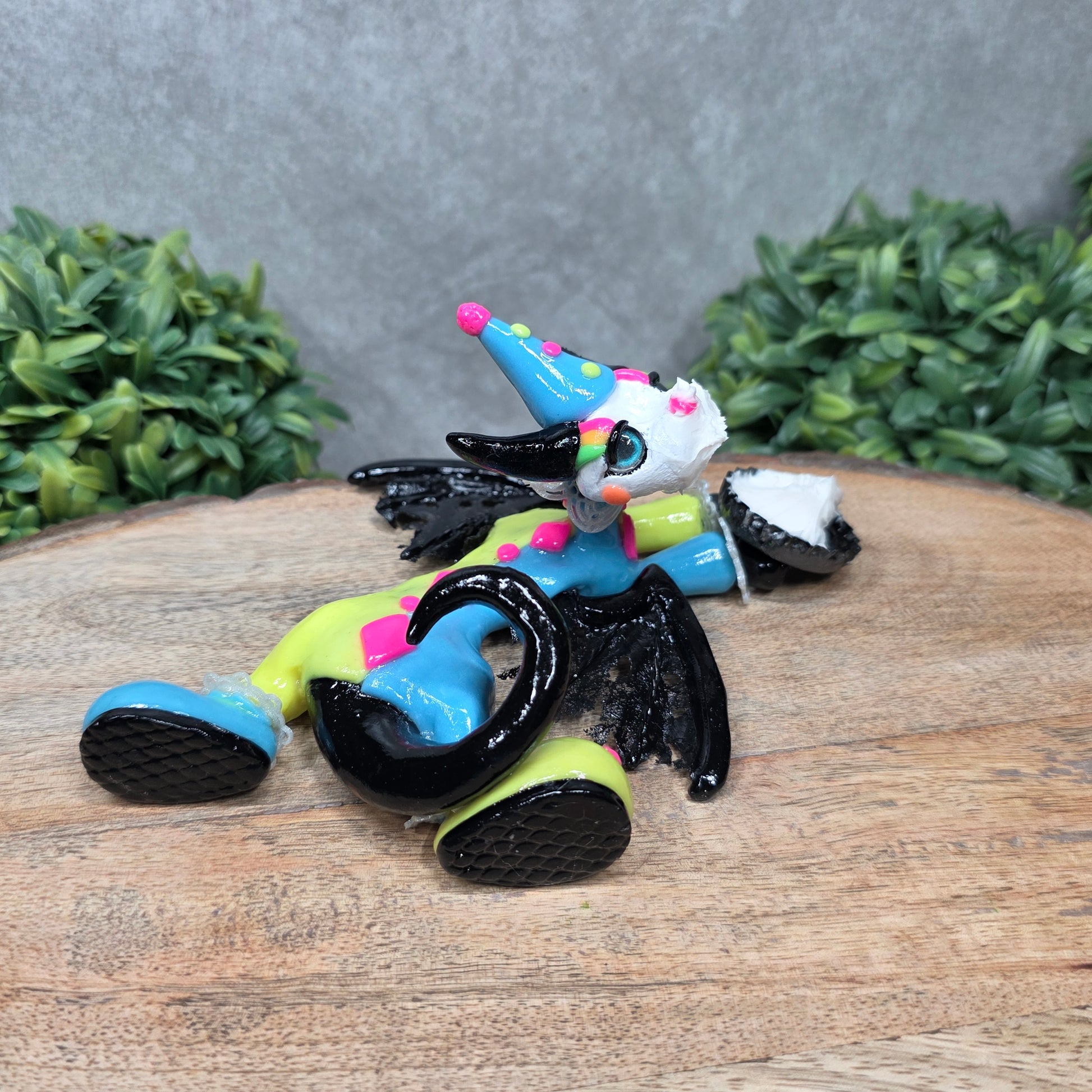 A clown dragon with cream pie on face on wood surface with greenery