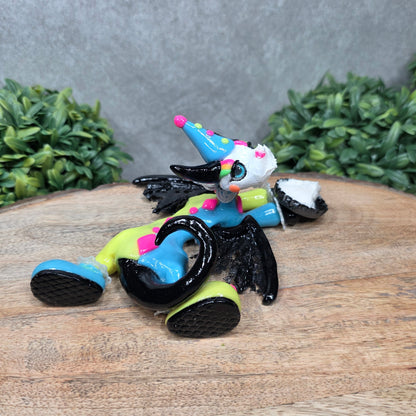 A clown dragon with cream pie on face on wood surface with greenery