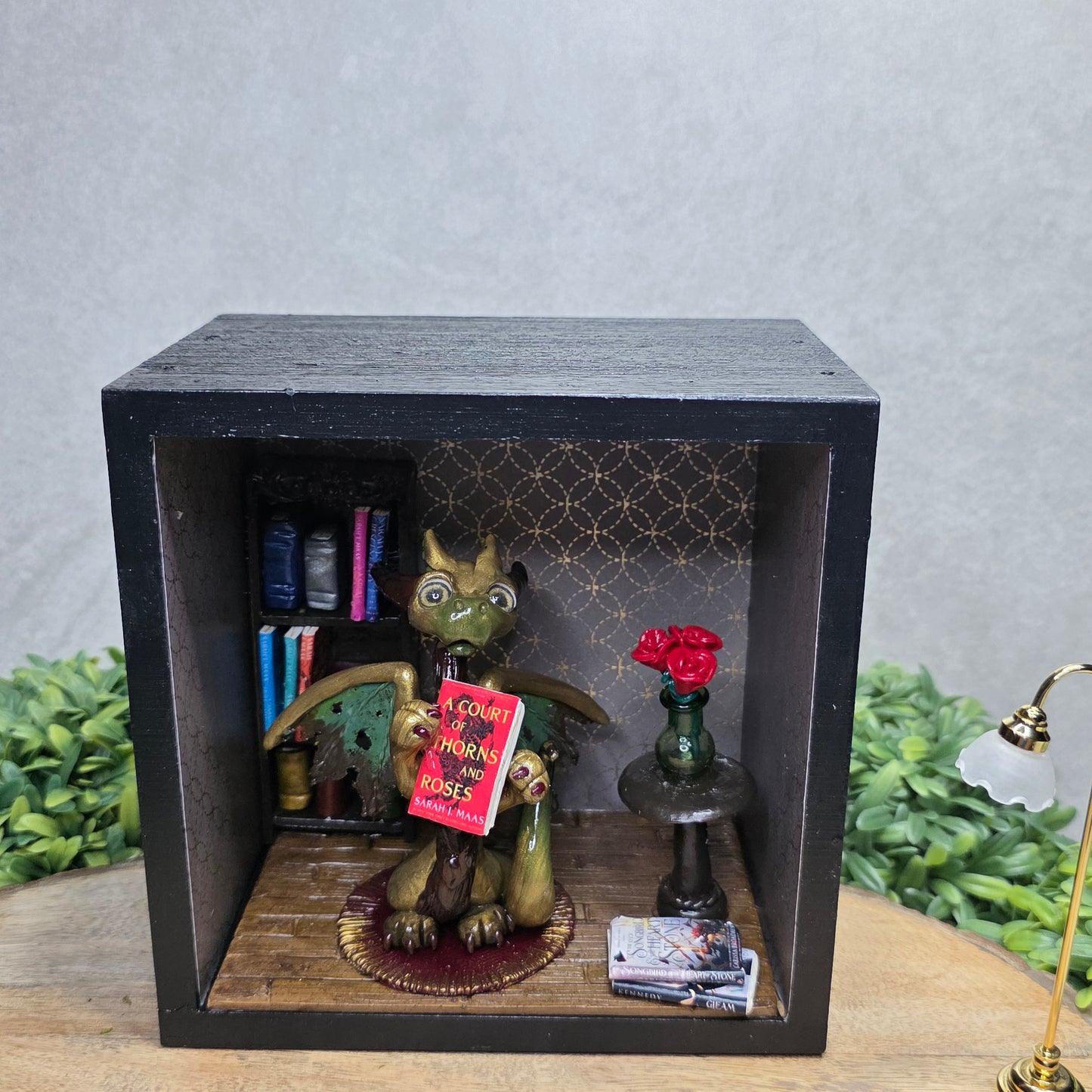 Book nook with dragon on a wood surface with greenery