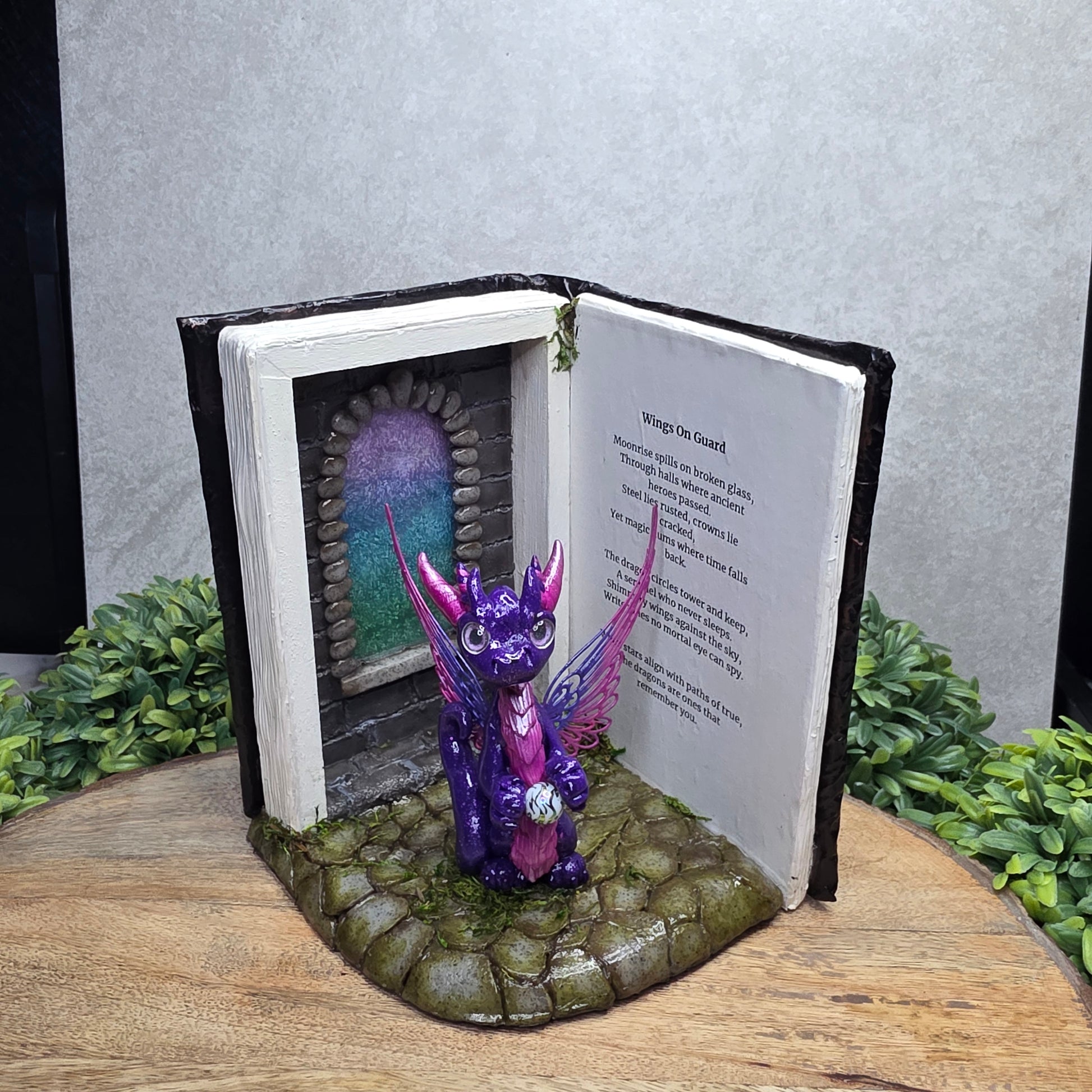 Book nook with fairy dragon on a wood surface with greenery