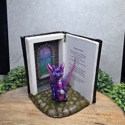 Book nook with fairy dragon on a wood surface with greenery