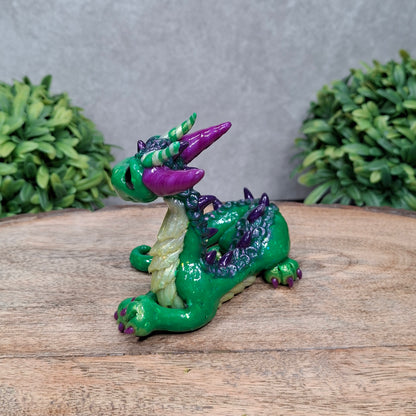 A clay dragon against a wood background with greenery
