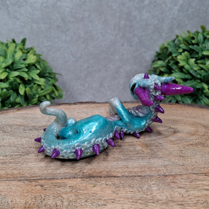 A clay dragon against a wood background with greenery