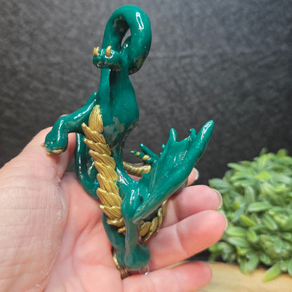 Hand holding a green and gold clay dragon