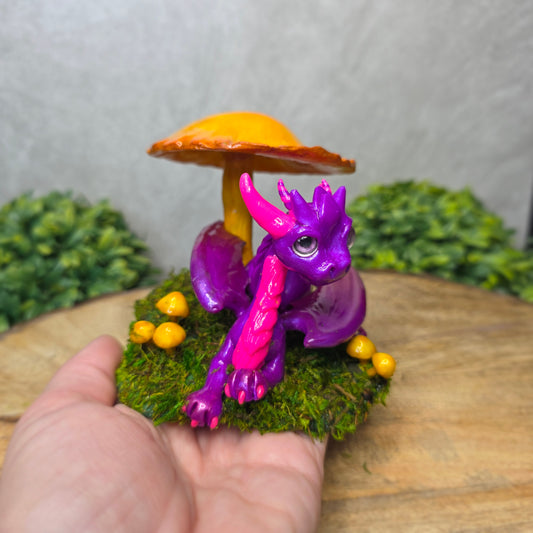 Purple dragon figurine on a yellow mushroom with green grass in the background