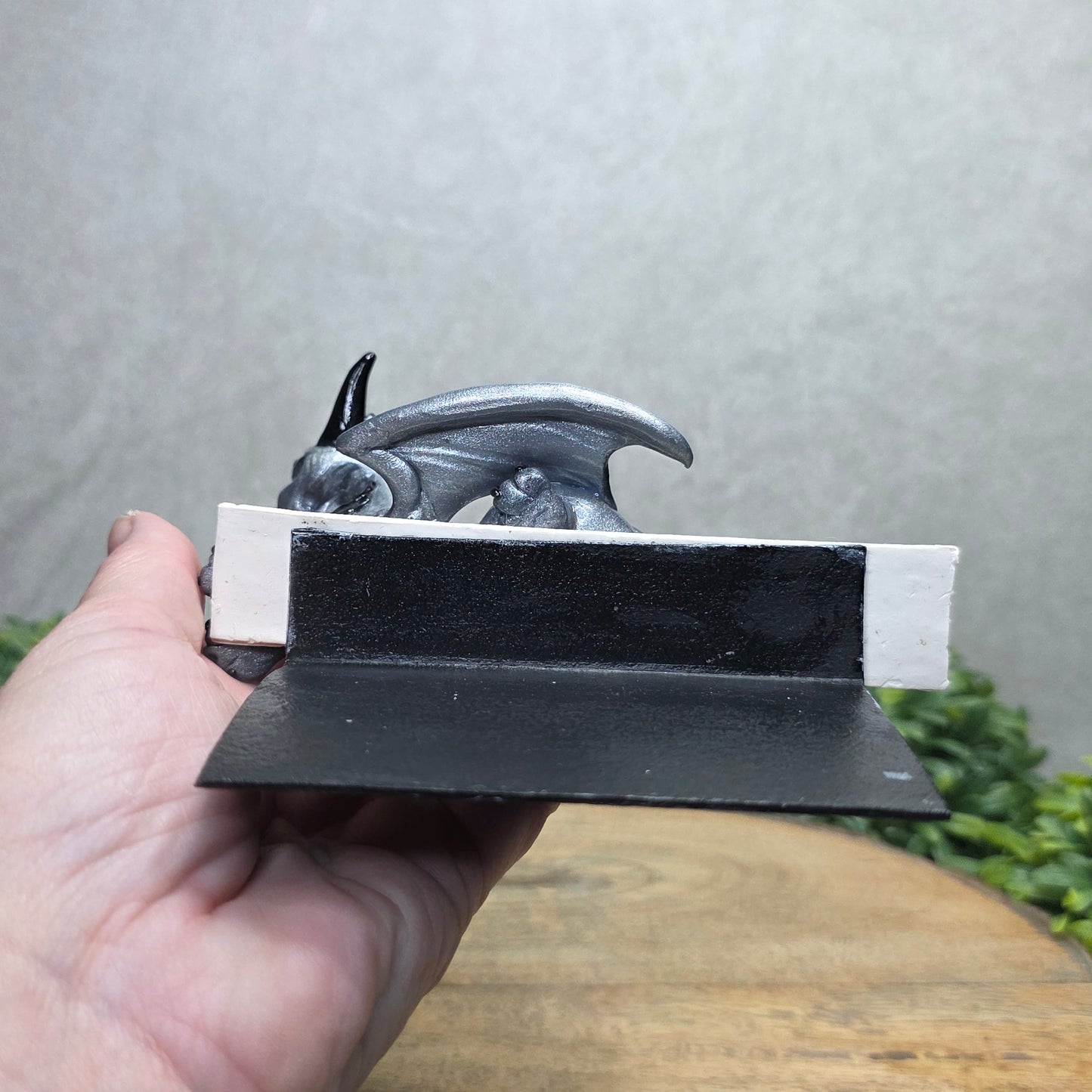 Hand holding a dragon book insert against a background with greenery