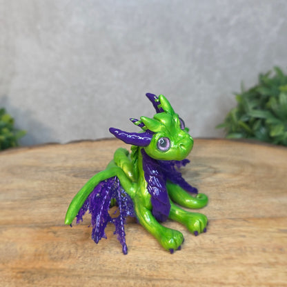 A green and purple clay dragon against a blurred wood surface