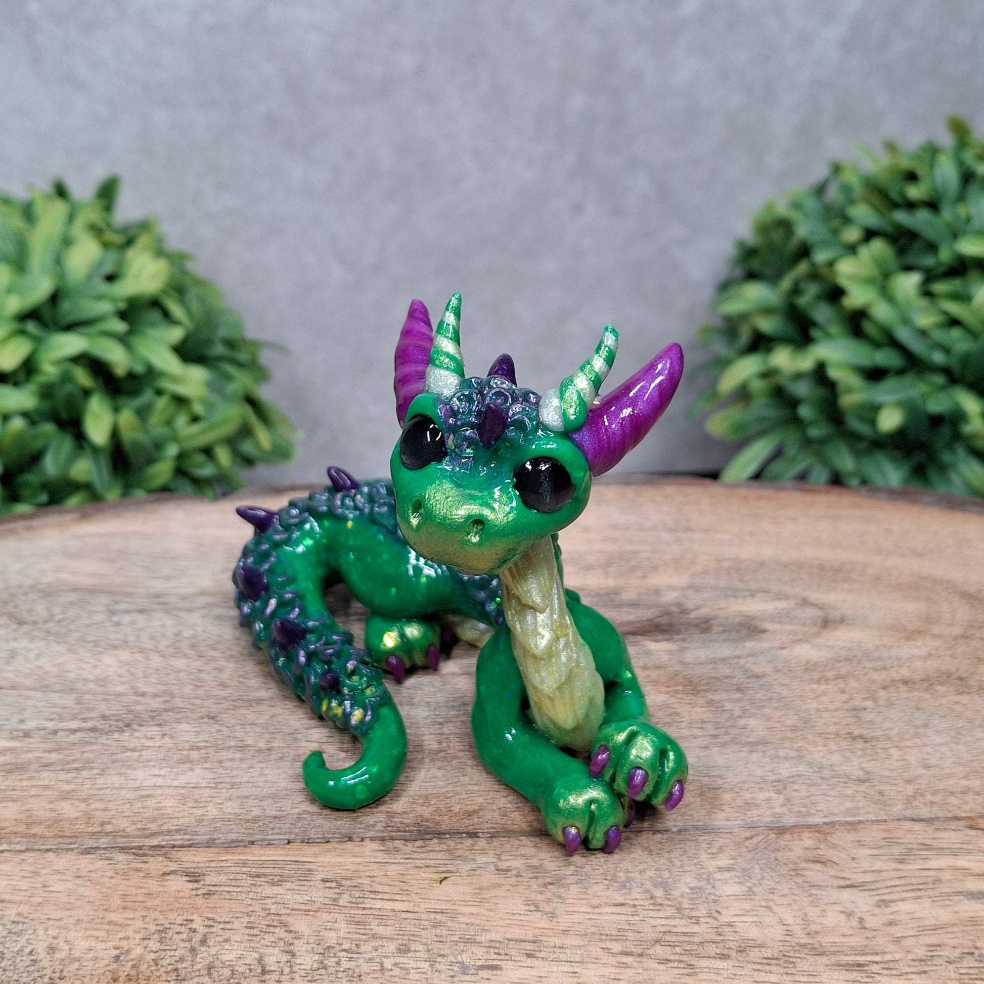 A clay dragon against a wood background with greenery