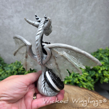 Back view of a  hand holding a  large clay dragon with cookies with a Wicked Winglings® watermark.