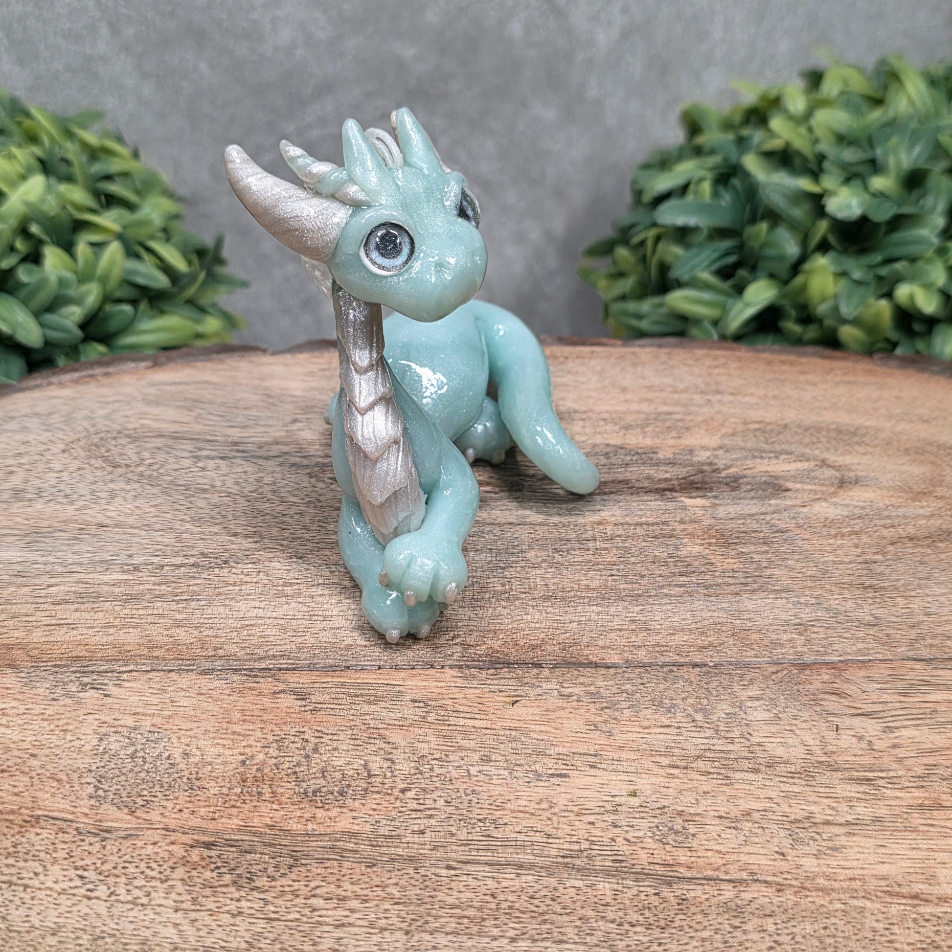 A dragon sculpture on wood surface with greenery