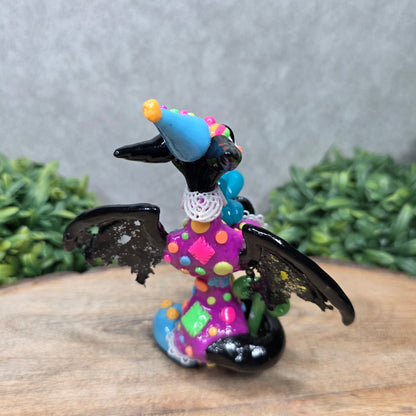 A clown dragon with balloon animals on wood surface with greenery
