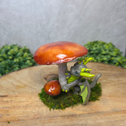 Small dragon figurine on a mushroom with greenery in the background
