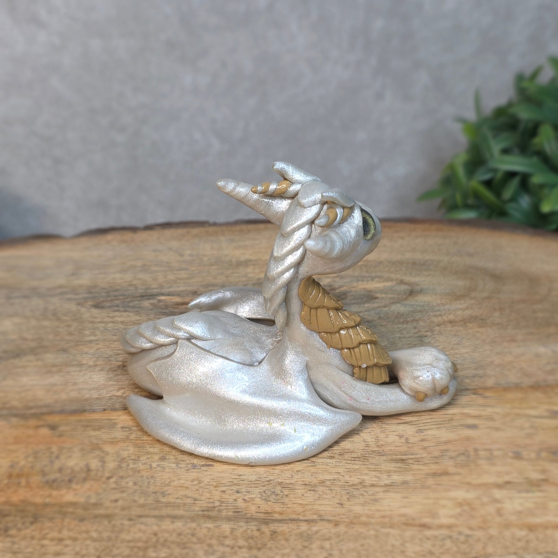A pearl and tan clay dragon against a blurred wood surface