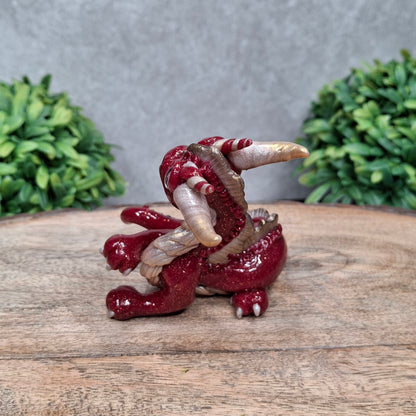 A clay dragon against a wood background with greenery