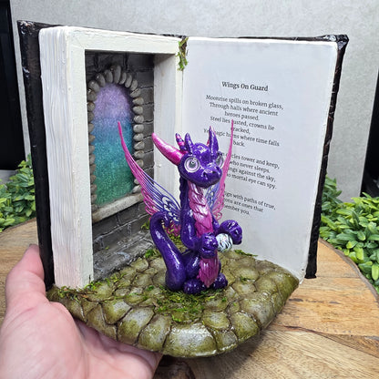 Hand holding an open book nook with fairy dragon