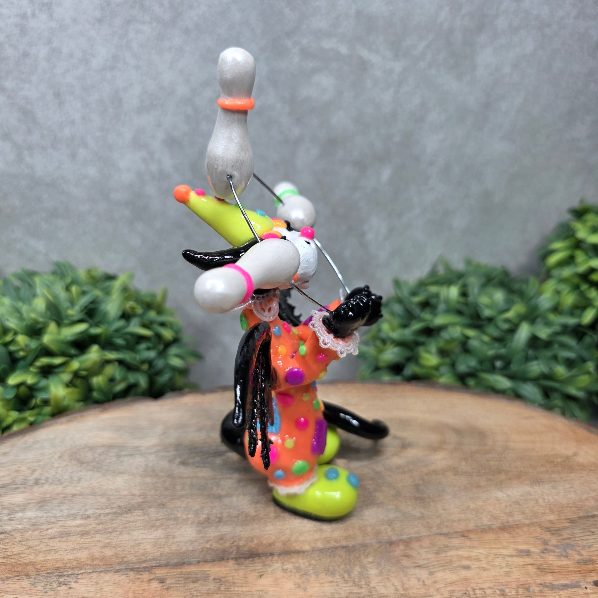 A clown dragon juggling on a wood surface with greenery