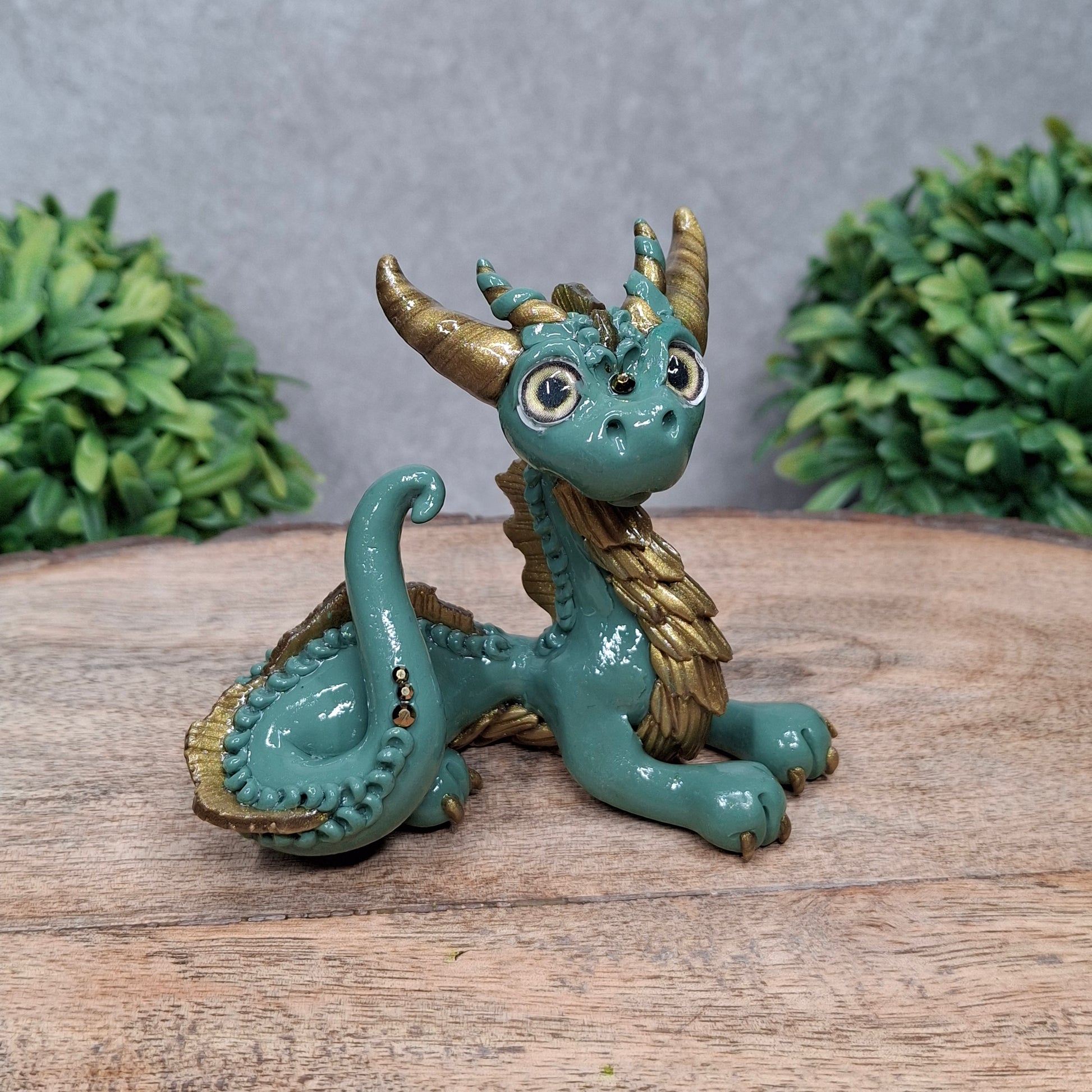  A clay dragon against a wood background with greenery