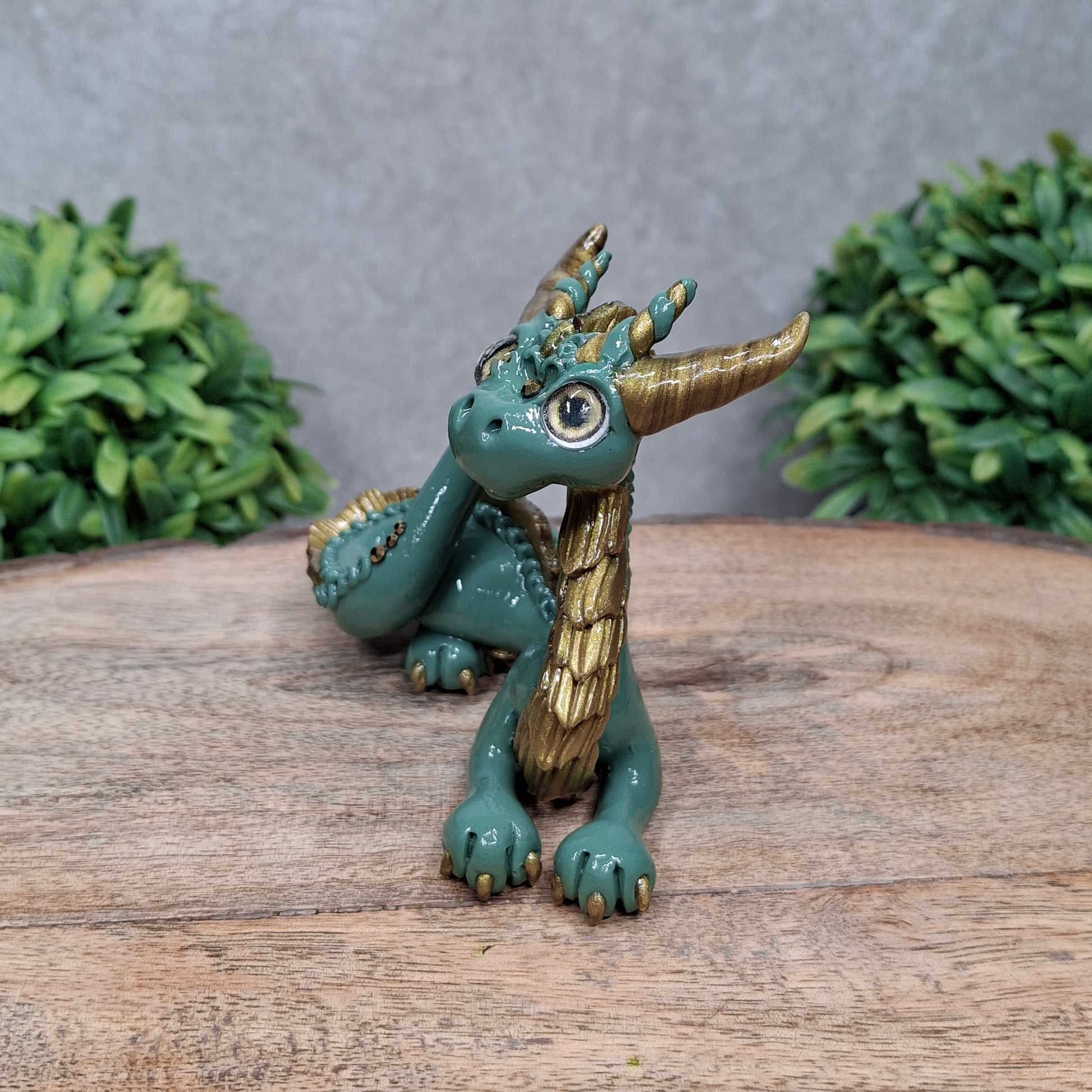 A clay dragon against a wood background with greenery