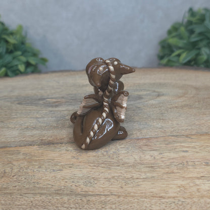 A baby polymer clay dragon with a chocolate truffle against a blurred background