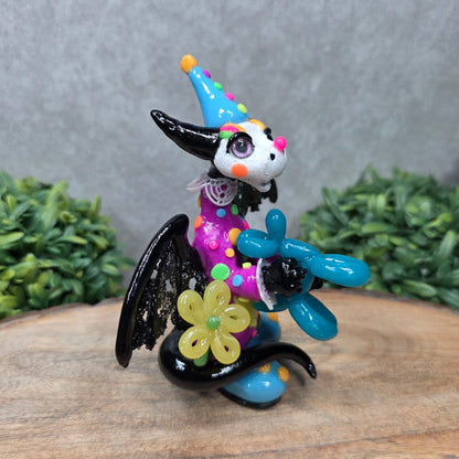 A clown dragon with balloon animals on wood surface with greenery