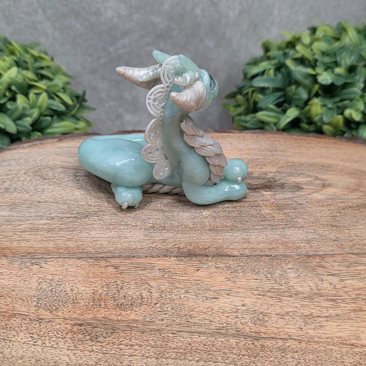 A dragon sculpture on wood surface with greenery