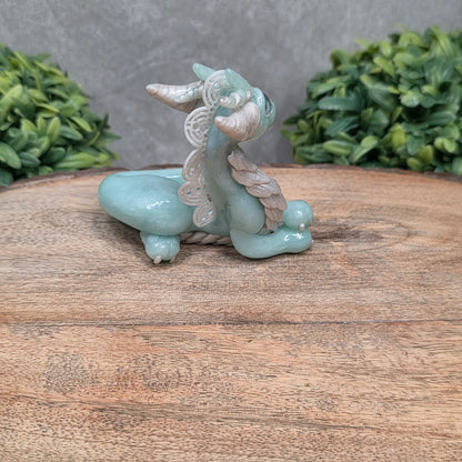 A dragon sculpture on wood surface with greenery
