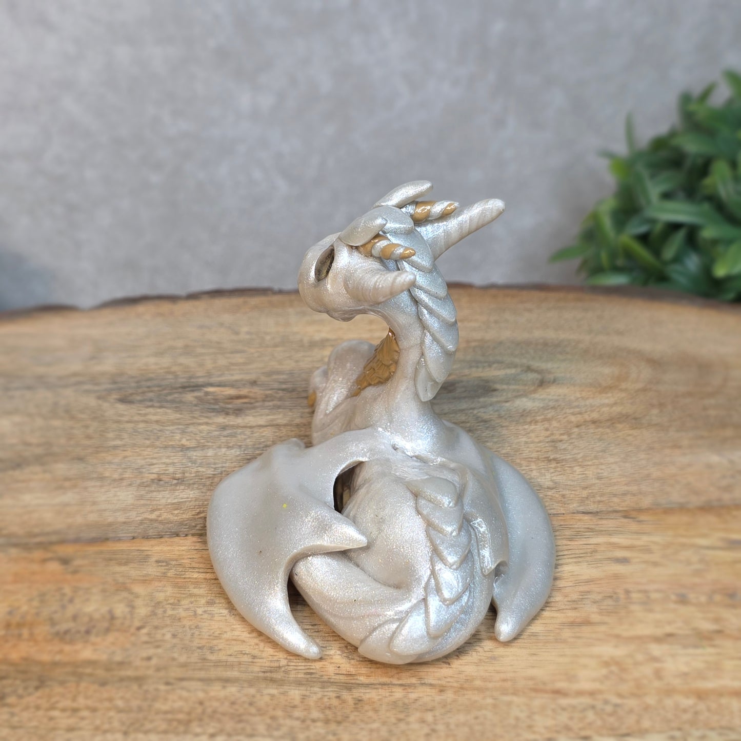 A pearl and tan clay dragon against a blurred wood surface