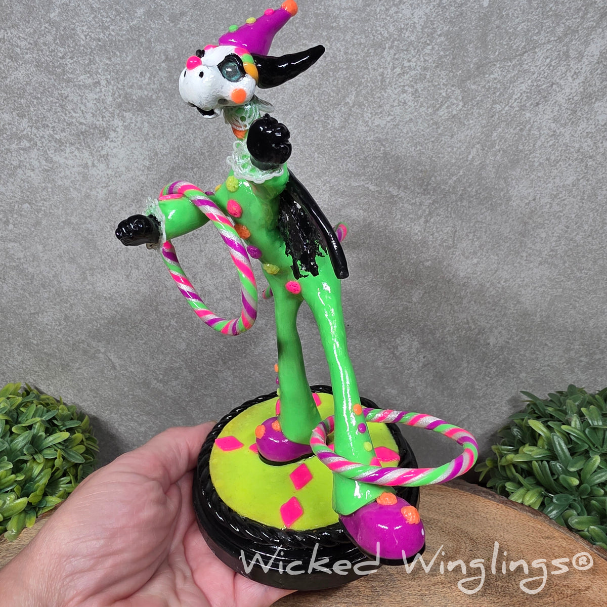 A clown dragon with hoola hoops on a wood surface with greenery