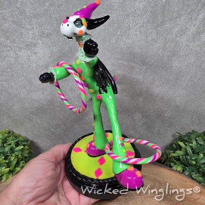 A clown dragon with hoola hoops on a wood surface with greenery