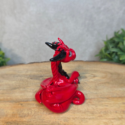 A red and black clay dragon against a blurred wood surface