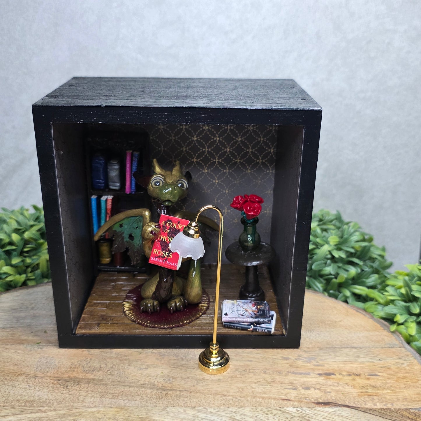 Book nook with dragon on a wood surface with greenery