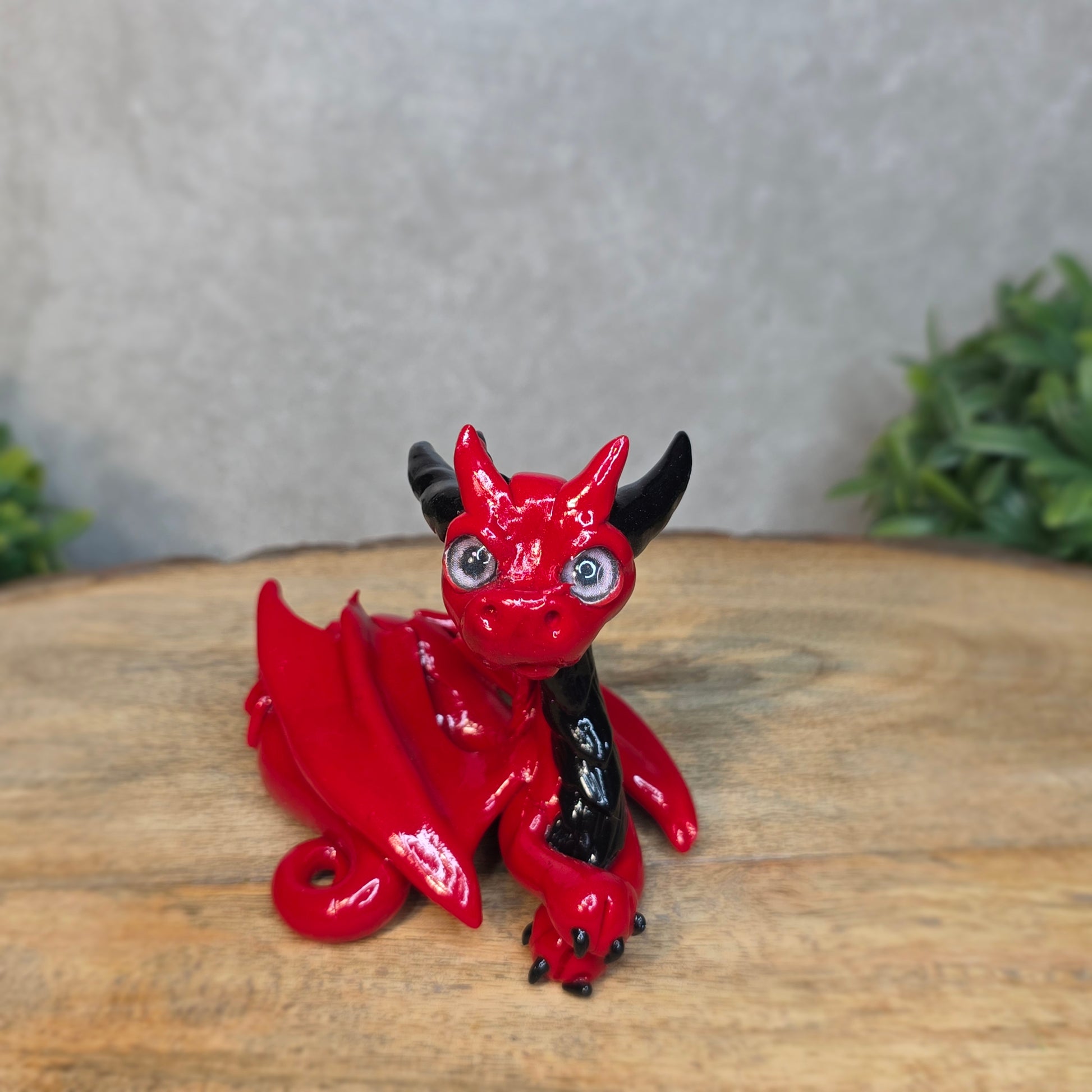 A red and black clay dragon against a blurred wood surface