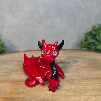 A red and black clay dragon against a blurred wood surface