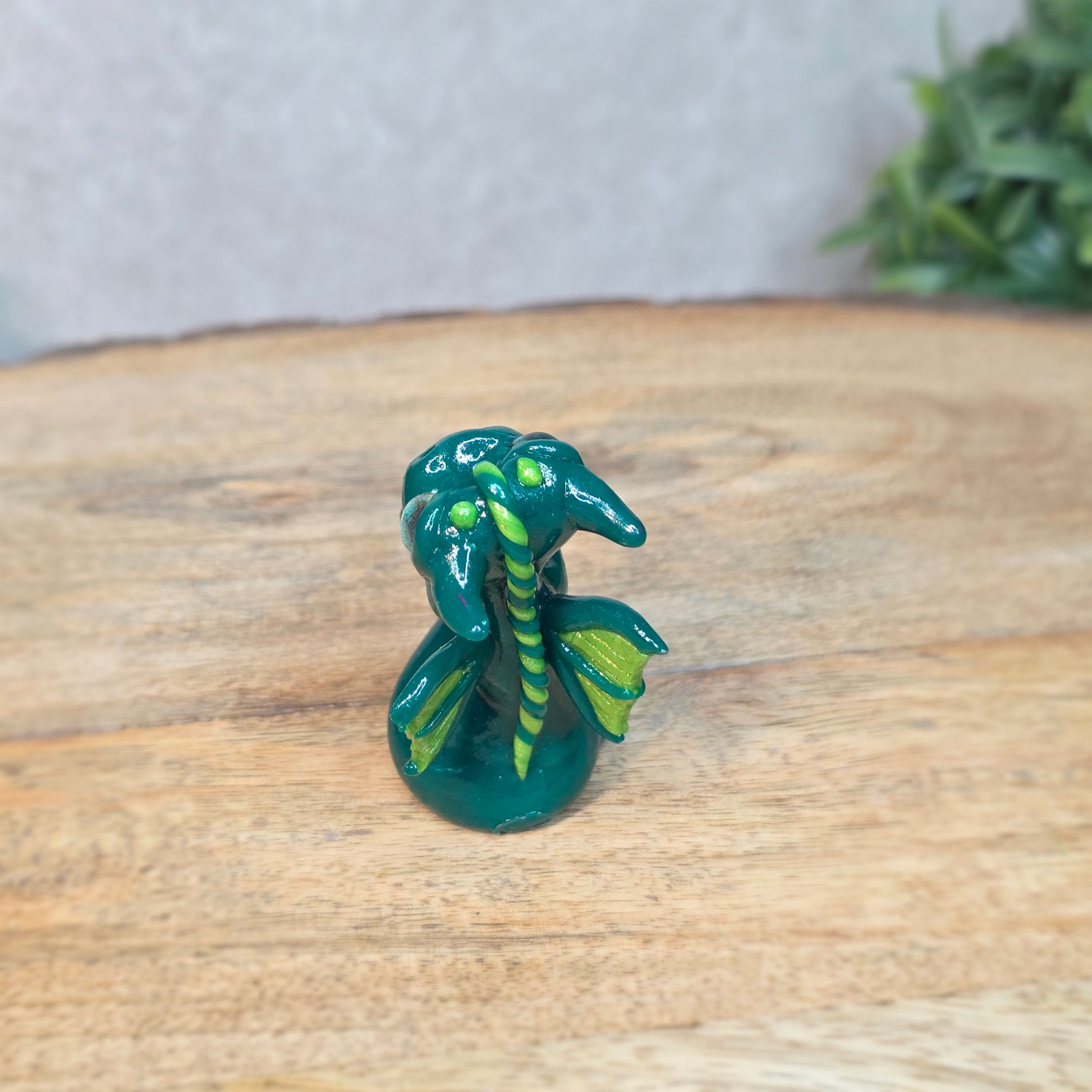 A small green dragon against a blurred wood background