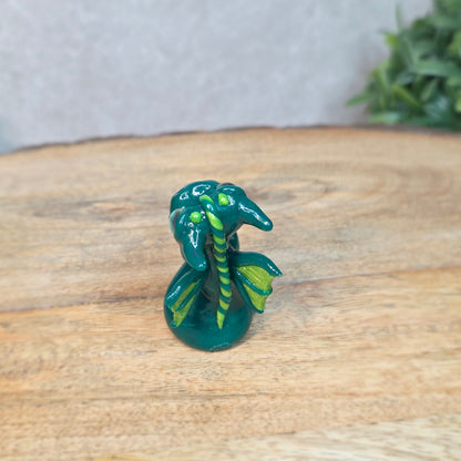 A small green dragon against a blurred wood background
