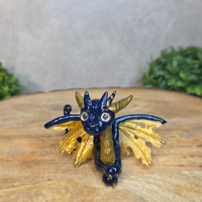 A blue and gold clay dragon against a blurred wood surface