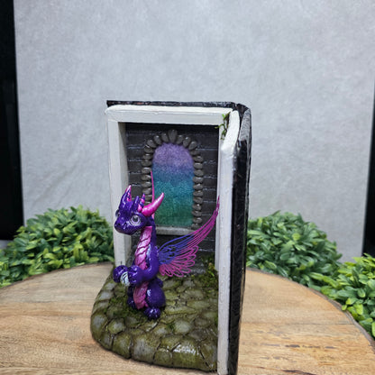 Book nook with fairy dragon on a wood surface with greenery