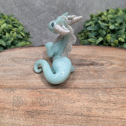 A dragon sculpture on wood surface with greenery
