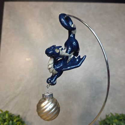 Hand holding a clay dragon with glass ornament against a blurred background