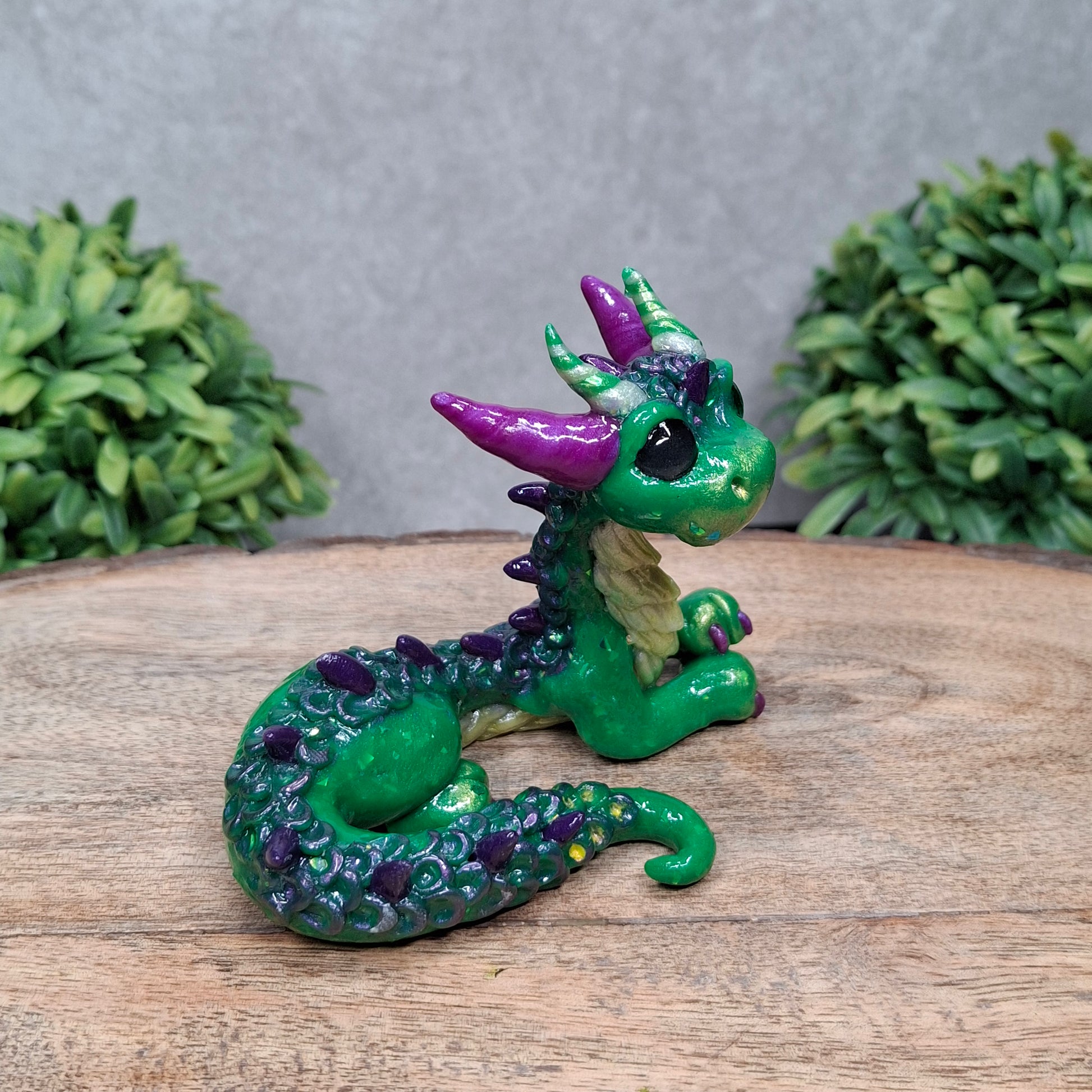 A clay dragon against a wood background with greenery
