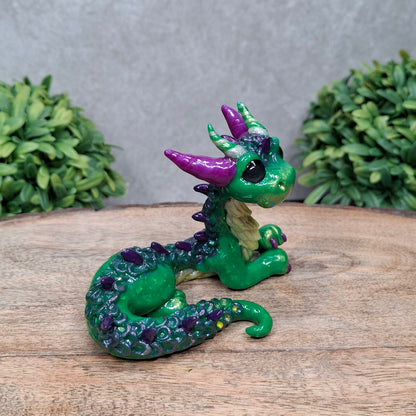 A clay dragon against a wood background with greenery