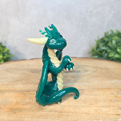 A green and cream clay dragon against a blurred wood surface
