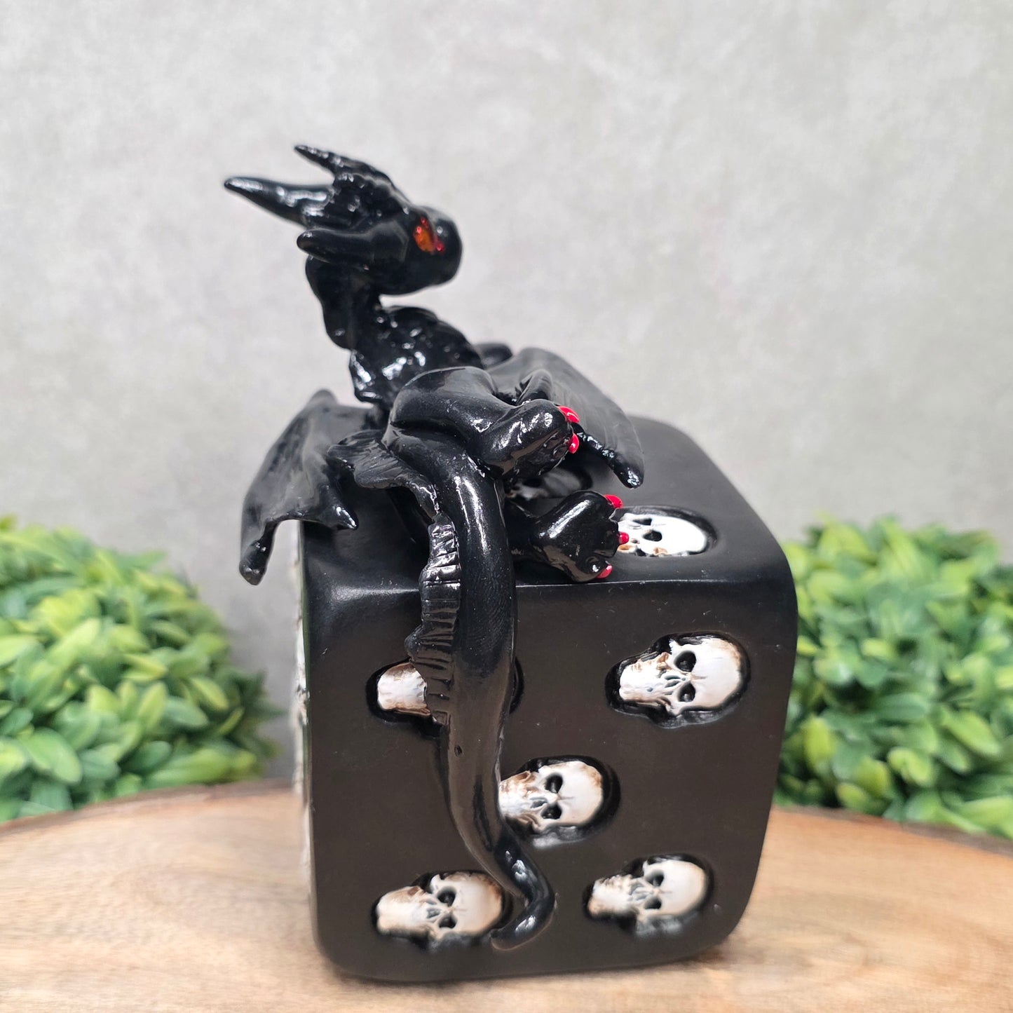 A clay dragon on a skull dice with greenery
