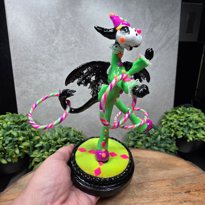 A clown dragon with hoola hoops on a wood surface with greenery
