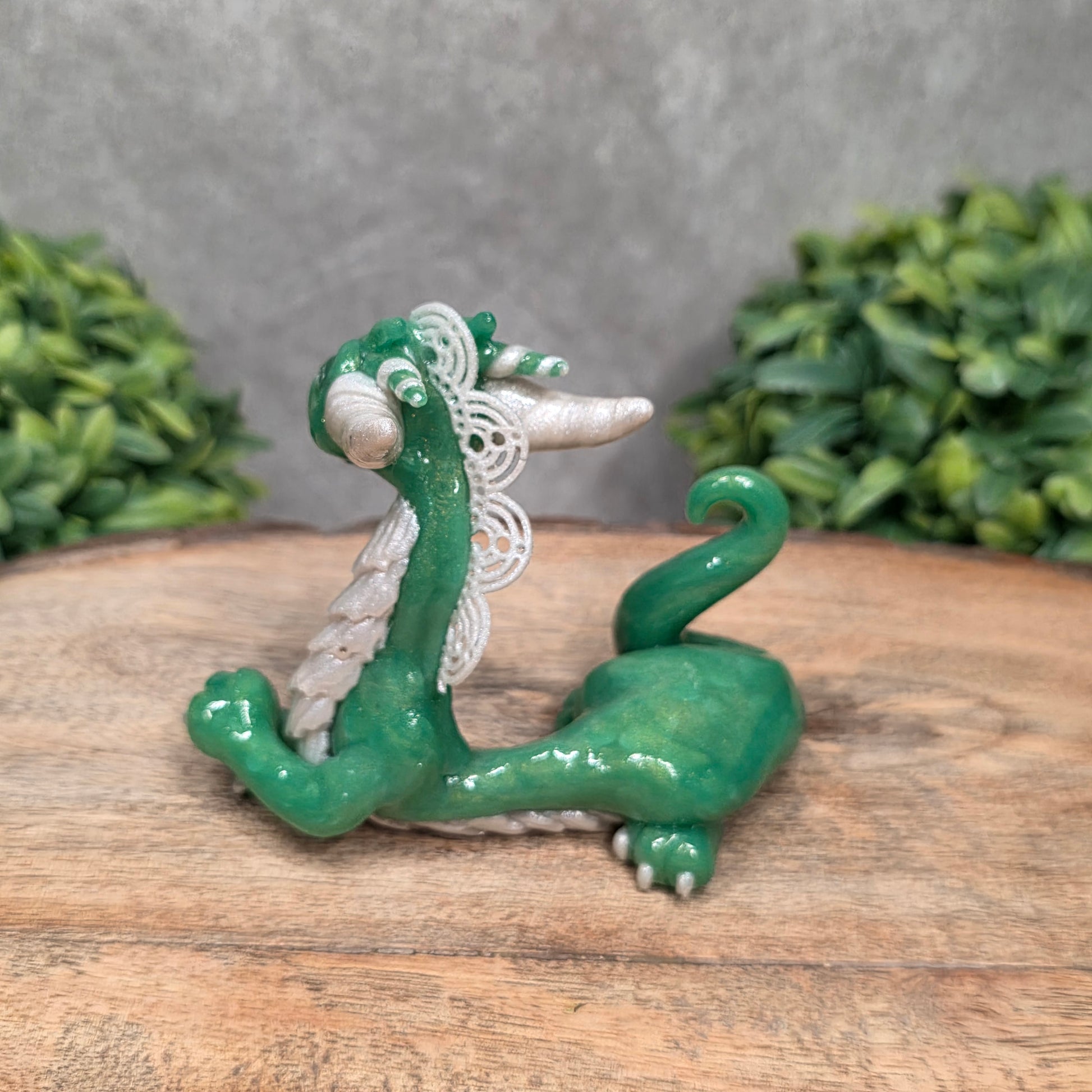 A dragon sculpture on wood surface with greenery
