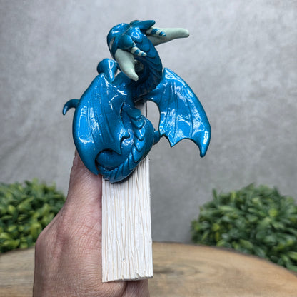 Hand holding a dragon book insert against a background with greenery