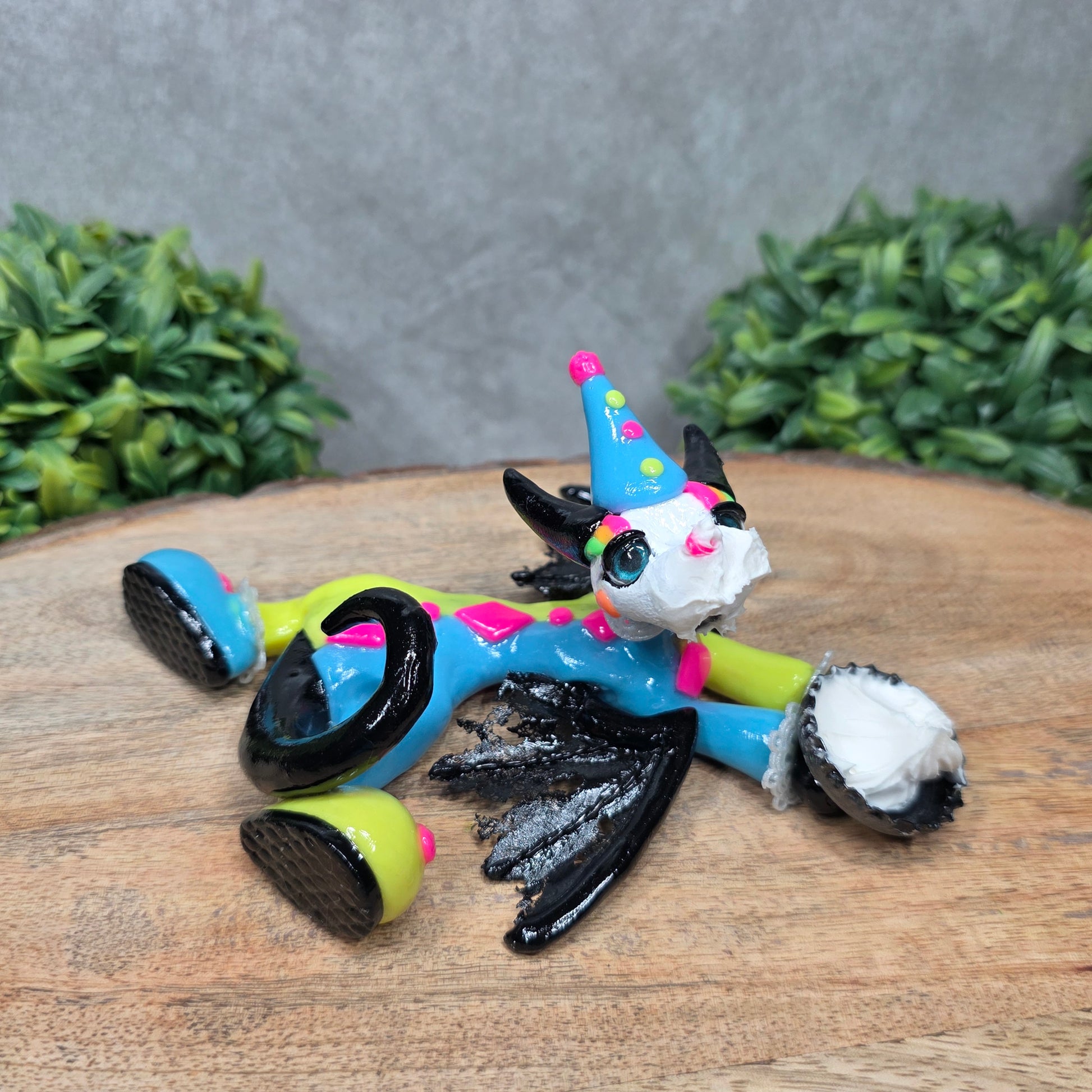A clown dragon with cream pie on face on wood surface with greenery