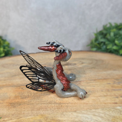 Fairy dragon on a wooden surface with a blurred green plant in the background