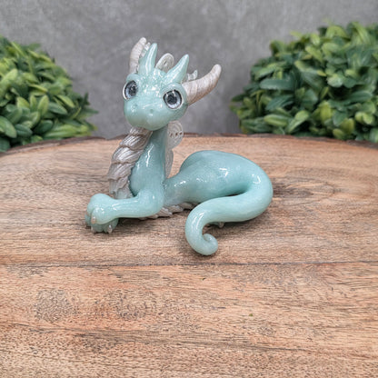 A dragon sculpture on wood surface with greenery